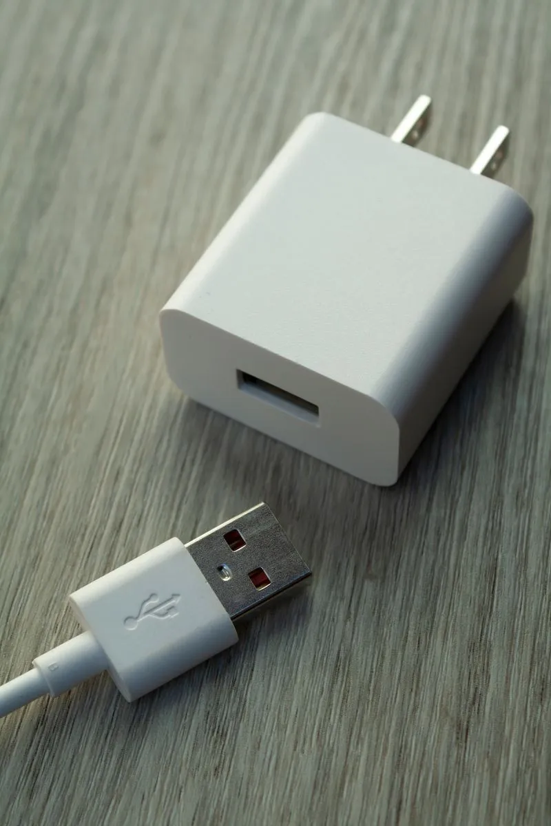 A white USB wall charger and cable on a wooden table